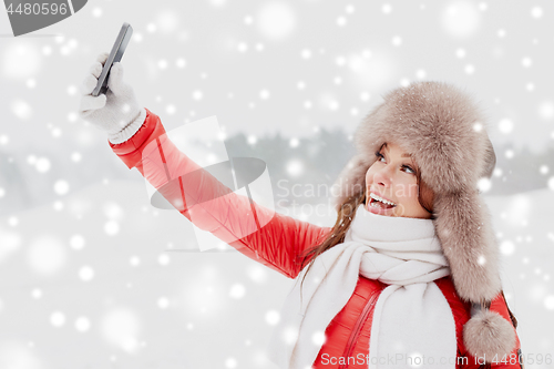 Image of happy woman taking selfie outdoors in winter