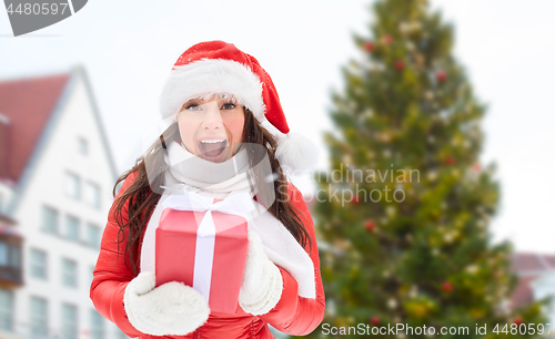 Image of happy woman with gift over christmas tree