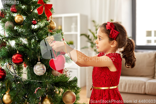 Image of little girl decorating christmas tree at home