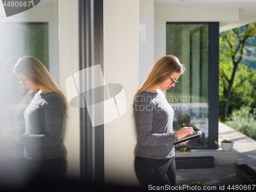 Image of women using tablet computer in front of luxury home villa