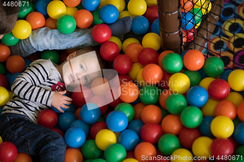 Image of boy having fun in hundreds of colorful plastic balls