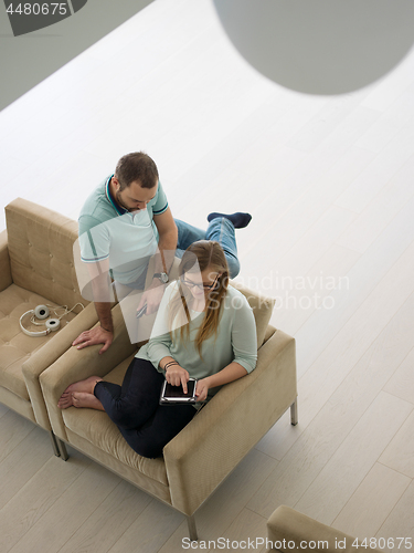 Image of couple relaxing at  home with tablet computers