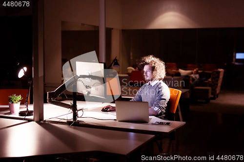 Image of man working on computer in dark office