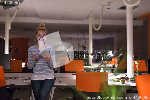 Image of woman working on digital tablet in night office