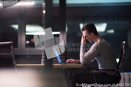 Image of man working on laptop in dark office