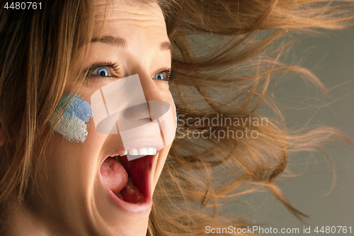 Image of Portrait of a woman with the flag of the Argentina painted on her face.