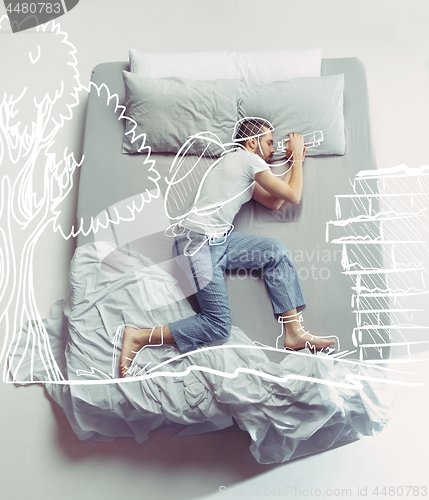 Image of Top view photo of young man sleeping in a big white bed and his dreams