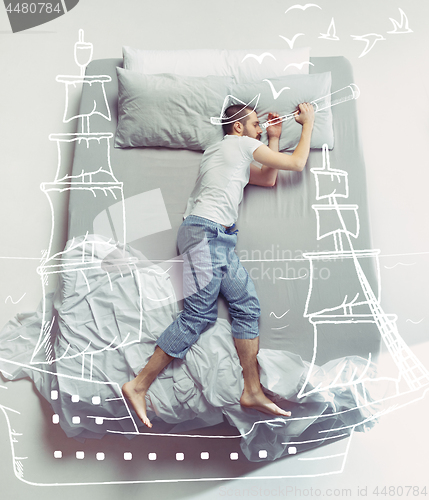Image of Top view photo of young man sleeping in a big white bed and his dreams.