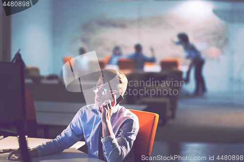 Image of man using mobile phone in dark office