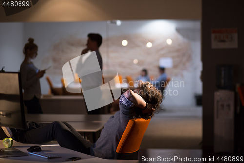 Image of businessman sitting with legs on desk at office