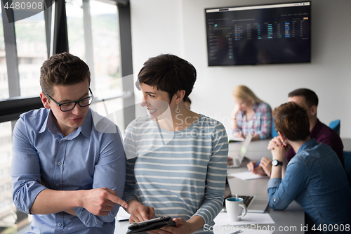 Image of Two Business People Working With Tablet in office