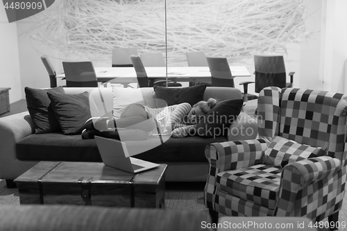 Image of woman sleeping on a sofa  in a creative office