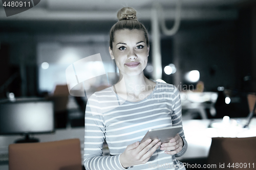 Image of woman working on digital tablet in night office