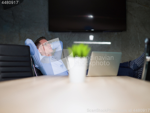 Image of businessman sitting with legs on desk at office