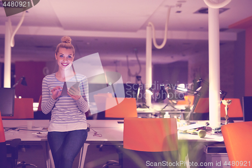 Image of woman working on digital tablet in night office