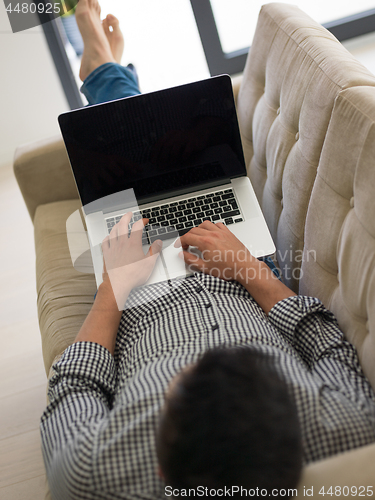 Image of Man using laptop in living room