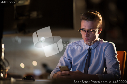 Image of man using mobile phone in dark office