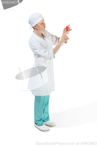 Image of beautiful young woman doctor in medical robe holding syringe in hand.