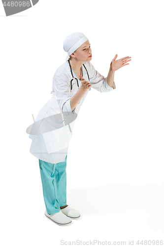 Image of Beautiful young woman is sending an air kiss in white coat posing at studio. Full length studio shot isolated on white.