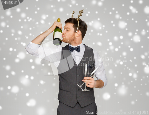 Image of man kissing bottle of champagne at christmas party