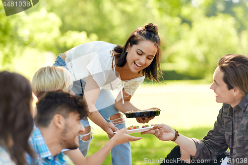 Image of friends with drinks and food at picnic in park