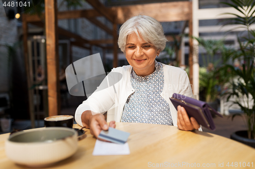 Image of senior woman with credit card paying bill at cafe