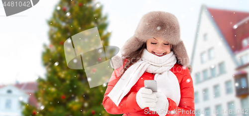 Image of woman with smartphone over christmas tree