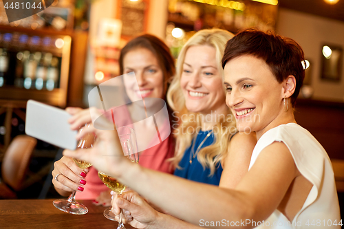 Image of women taking selfie by smartphone at wine bar