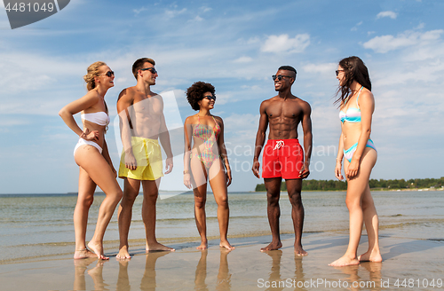 Image of happy friends hugging on summer beach
