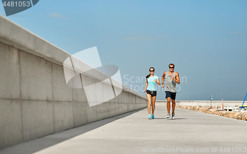 Image of couple in sports clothes running outdoors