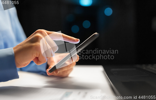 Image of close up of hands with smartphone at night office