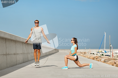 Image of happy couple warming up on pier before training