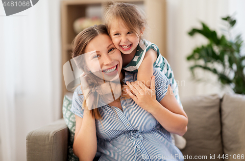 Image of pregnant mother and daughter hugging at home