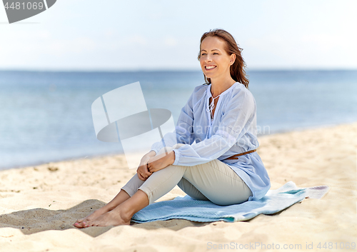 Image of happy woman sitting on summer beach