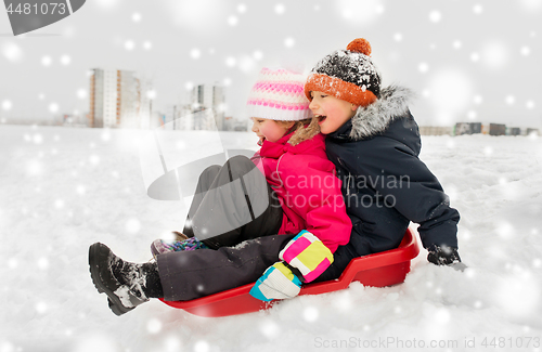 Image of little kids sliding on sled down hill in winter