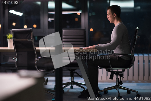 Image of man working on laptop in dark office