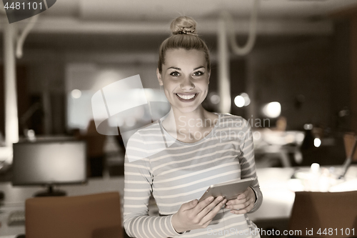 Image of woman working on digital tablet in night office