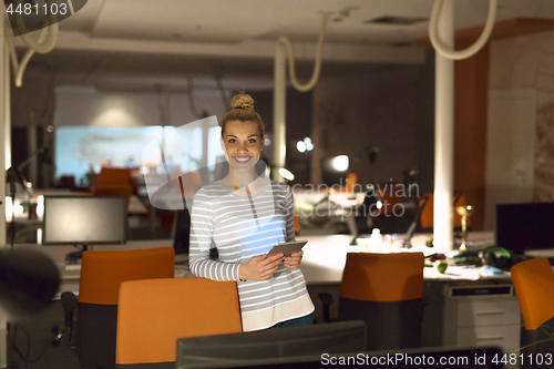 Image of woman working on digital tablet in night office