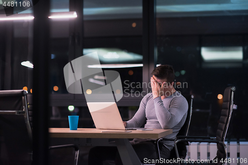 Image of man working on laptop in dark office