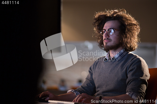 Image of man working on computer in dark office