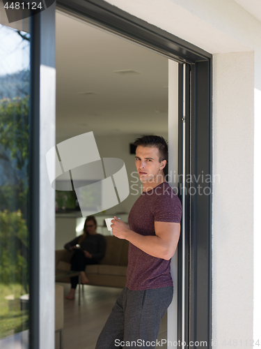 Image of man drinking coffee in front of her luxury home villa