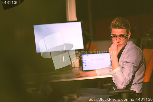 Image of man working on computer in dark office