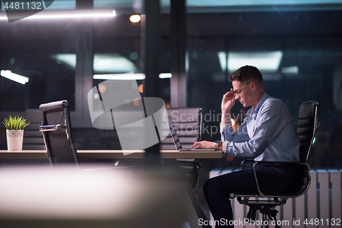 Image of man working on laptop in dark office