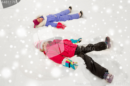 Image of happy little girls making snow angels in winter