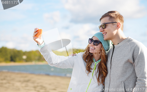 Image of happy teenage couple taking selfie by smartphone