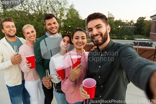 Image of friends with drinks taking selfie at rooftop party