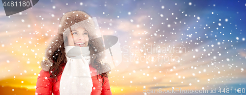 Image of happy woman in winter fur hat over sky and snow