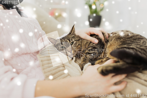 Image of close up of owner with tabby cat in bed over snow