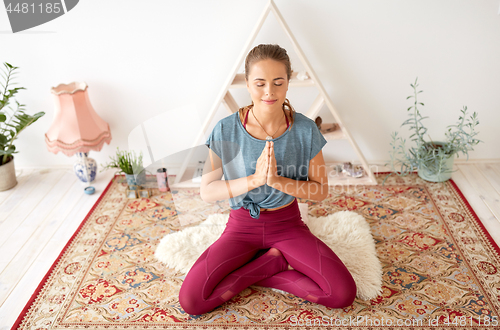 Image of woman meditating in lotus pose at yoga studio