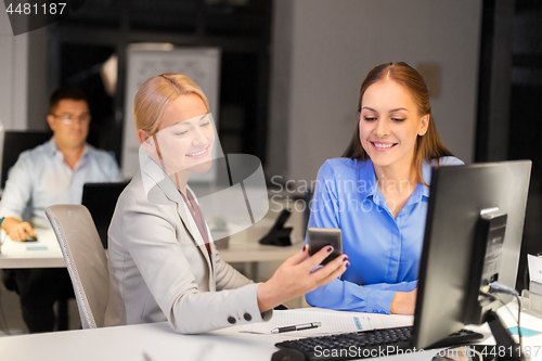 Image of businesswomen with smartphone late at night office